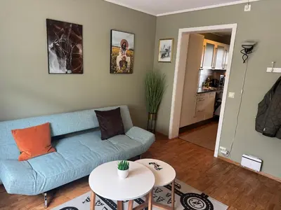 a living room with a blue couch and a table at Sentralt leilighet in Ålesund