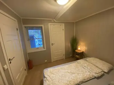 a bedroom with a bed and a window and a door at Sentralt leilighet in Ålesund