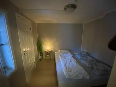 a small bedroom with a bed and a lamp on a table at Sentralt leilighet in Ålesund