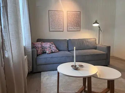 a living room with a couch and a table with a candle at Koselig leilighet i Ålesund sentrum in Ålesund