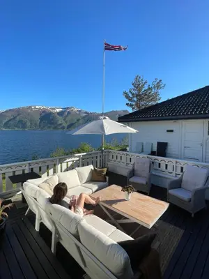 a woman sitting on a couch on a deck at Fjordhus in Austerheim