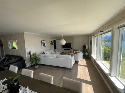 a living room with white furniture and large windows at Fjordhus in Austerheim