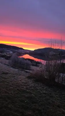 a sunset over a field with a body of water at Knobelauch Family Home, Valdres in Vøle