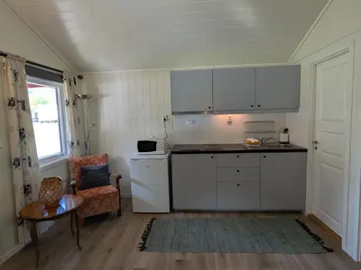 a kitchen with white appliances and a table and a chair at Oldevatn Camping in Olden