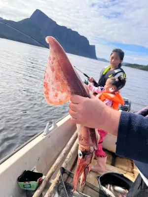 a person holding a large fish in a boat at Øen Hytter - Hytte 2 in Sørbø