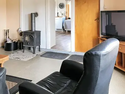 a living room with a black leather chair and a stove at 11 person holiday home in Bud-By Traum in Bud