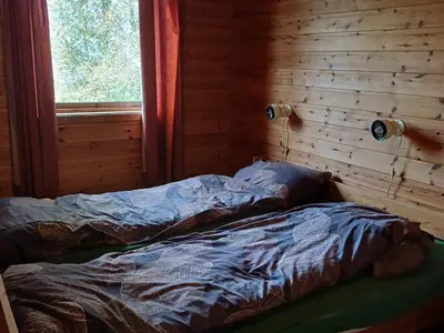 an unmade bed in a log cabin with a window at 7 person holiday home in Skjold-By Traum in Skjold