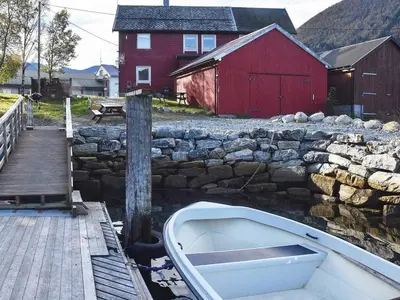 a boat sitting next to a stone wall and a red barn at 2 person holiday home in Måndalen-By Traum in Sæbø
