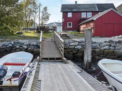 a boat on a dock next to a red barn at 4 person holiday home in Måndalen-By Traum in Sæbø