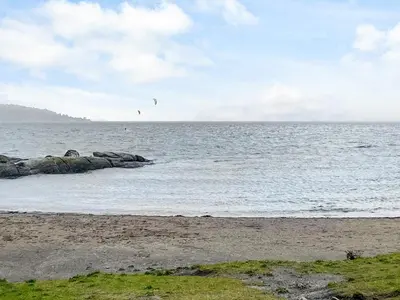 a beach with two birds flying over the water at 5 person holiday home in Brekke-By Traum in Dingja