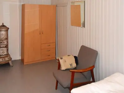a bedroom with a chair and a bed and a cabinet at 11 person holiday home in Fjørtoft-By Traum in Fjørtoft