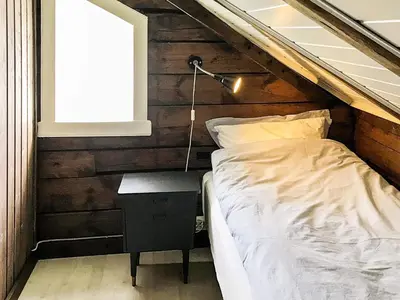 a bedroom with a bed and a lamp and a window at 11 person holiday home in Fjørtoft-By Traum in Fjørtoft