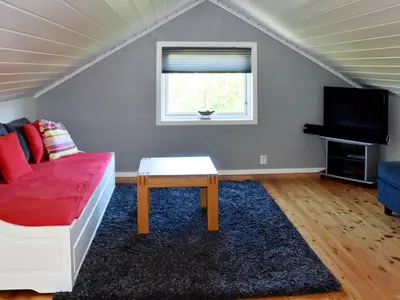 a living room with a red couch and a tv at 9 person holiday home in Farstad-By Traum in Farstad