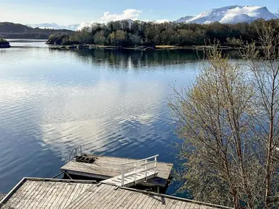 a dock on a lake with mountains in the background at 9 person holiday home in GURSKØY-By Traum in Kjellsund