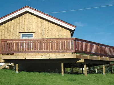 a large wooden deck on a house in a field at 4 person holiday home in VÅGLAND-By Traum in Rabben