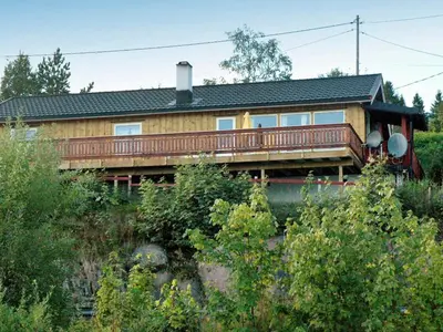 a wooden house with a deck on a hill at 4 person holiday home in VÅGLAND-By Traum in Rabben