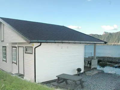 a white building with a bench next to the water at 4 person holiday home in Lauvstad-By Traum in Lauvstad
