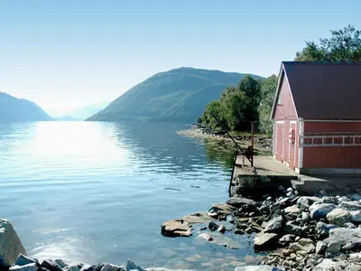 a red building next to a body of water at 4 person holiday home in Lauvstad-By Traum in Lauvstad