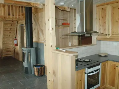 a kitchen with wooden walls and a stove in it at 7 person holiday home in Blaksæter-By Traum in Sølberg