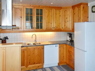 a kitchen with wooden cabinets and a white refrigerator at 7 person holiday home in Blaksæter-By Traum in Sølberg