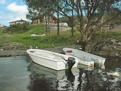 a white boat sitting in the water next to a house at 8 person holiday home in VEVANG-By Traum in Vevang