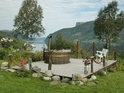 a woman sitting on a wooden deck with a hot tub at 11 person holiday home in Syvde in Myklebost