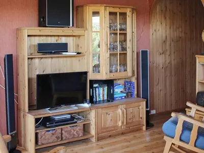 a living room with a wooden entertainment center with a television at 12 person holiday home in Kvenvær in Kvenvær