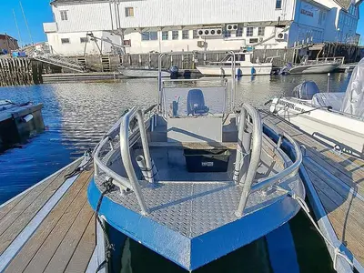 a blue boat is docked at a dock at 12 person holiday home in Kvenvær in Kvenvær
