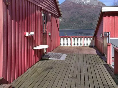 a red building with a bench on the side of it at 6 person holiday home in Halsanaustan in Korsnes