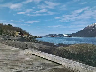 a wooden path next to a body of water with a boat at 6 person holiday home in Halsanaustan in Korsnes