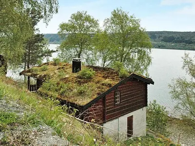 an old house with grass on the roof next to a lake at 4 person holiday home in Surna in Glerem