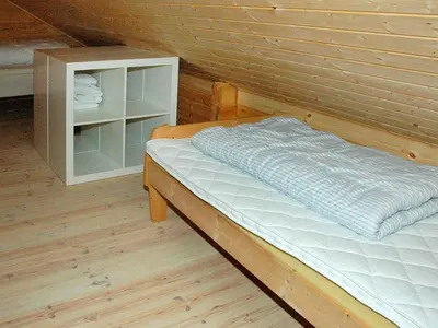 a bed in a room with a wooden wall at 5 person holiday home in VÅGLAND in Bårdset