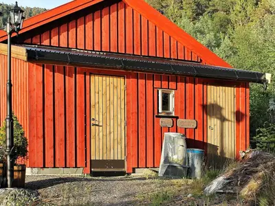 a red barn with an orange roof at 5 person holiday home in VÅGLAND in Bårdset
