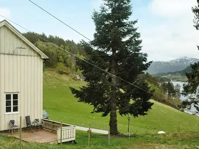 a tree on a deck next to a house at 5 person holiday home in VÅGLAND in Bårdset