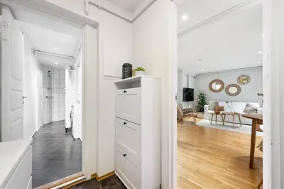a kitchen with white cabinets and a living room at Charming apartment 200m from Bryggen in Bergen