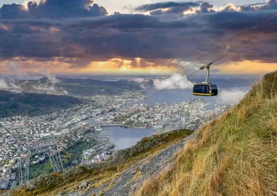 a gondola flying over a city on a hill at Charming apartment 200m from Bryggen in Bergen