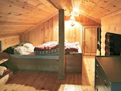 a bedroom with a bed in a wooden cabin at 11 person holiday home in Edland in Vågsli