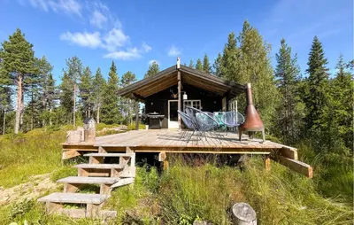 a wooden deck with a building in the woods at Cozy Home In Vinje With Wifi in Hommo