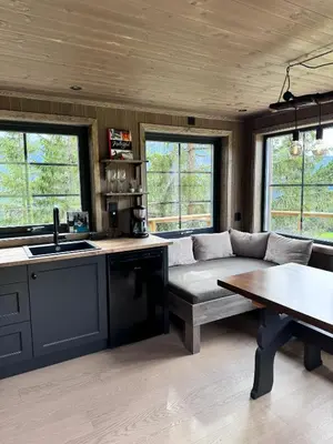 a kitchen and living room with a couch and a table at Fjellgla tretopphytte in Holo