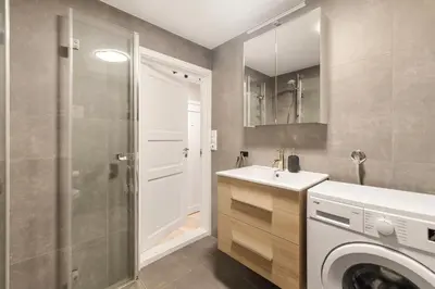 a bathroom with a sink and a washing machine at Central and modern apartment in Trondheim