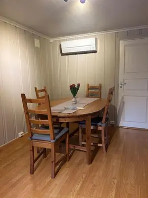 a dining room table with chairs and a vase of flowers on it at Sokkel-leilighet med nærhet til sentrum og Hovden skiheis in Oppdal