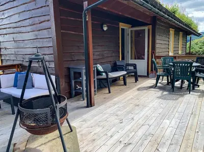 a wooden deck with chairs and tables on a cabin at Spacious cabin with a fabulous view and a sauna in Skulestadmo