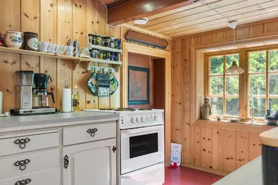 a kitchen with wooden walls and a white stove top oven at Charming cabin retreat by the coast in Midsund in Midsund