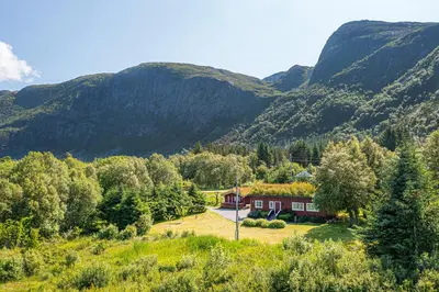 a house in the middle of a valley with mountains at Charming cabin retreat by the coast in Midsund in Midsund