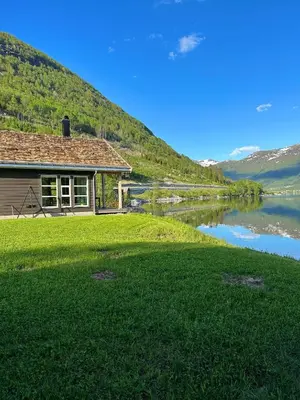 a house on the side of a river next to a lake at Holiday cabins with unmatched lake view in Jølster in Skei