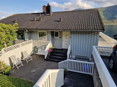 a white house with a porch with chairs and stairs at Hessahuset in Ålesund