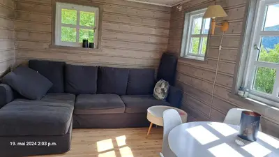 a living room with a blue couch and two windows at Kårhus på småbruk in Lia