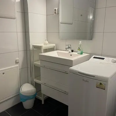 a white bathroom with a sink and a mirror at Engen 6 in Bergen