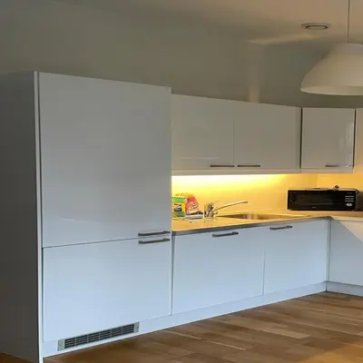 a white kitchen with white cabinets and a sink at Engen 6 in Bergen