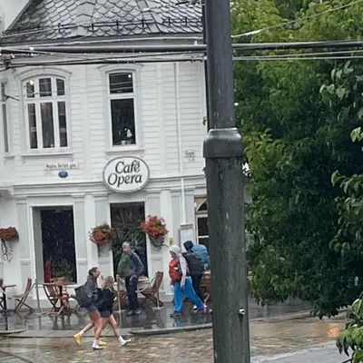a group of people walking in the rain in front of a building at Engen 6 in Bergen